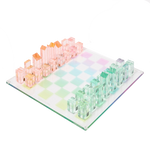 The Sunnylife Lucite Chess and Checkers, Aurora set by Sunnylife showcases a retro style with transparent pink and green pieces arranged on a pastel checkered board, exuding a kaleidoscopic color charm.