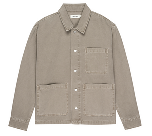 The Frame Canvas Chore Coat, in light brown cotton canvas with a collar and three front patch pockets, is displayed flat against a white background.