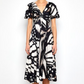 A woman wears the Prabal Gurung Flutter Slv Twist Dress, featuring black and white abstract print, short flutter sleeves, and a V-neckline, against a plain white background.