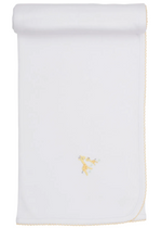 The Premier Giraffe Love Hand Emb. Blanket by Kissy Kissy is a white baby blanket crafted from 100% Pima cotton, featuring a hand-embroidered yellow giraffe illustration in the center and yellow scalloped edging, displayed rolled at the top.