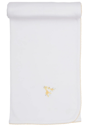 The Premier Giraffe Love Hand Emb. Blanket by Kissy Kissy is a white baby blanket crafted from 100% Pima cotton, featuring a hand-embroidered yellow giraffe illustration in the center and yellow scalloped edging, displayed rolled at the top.