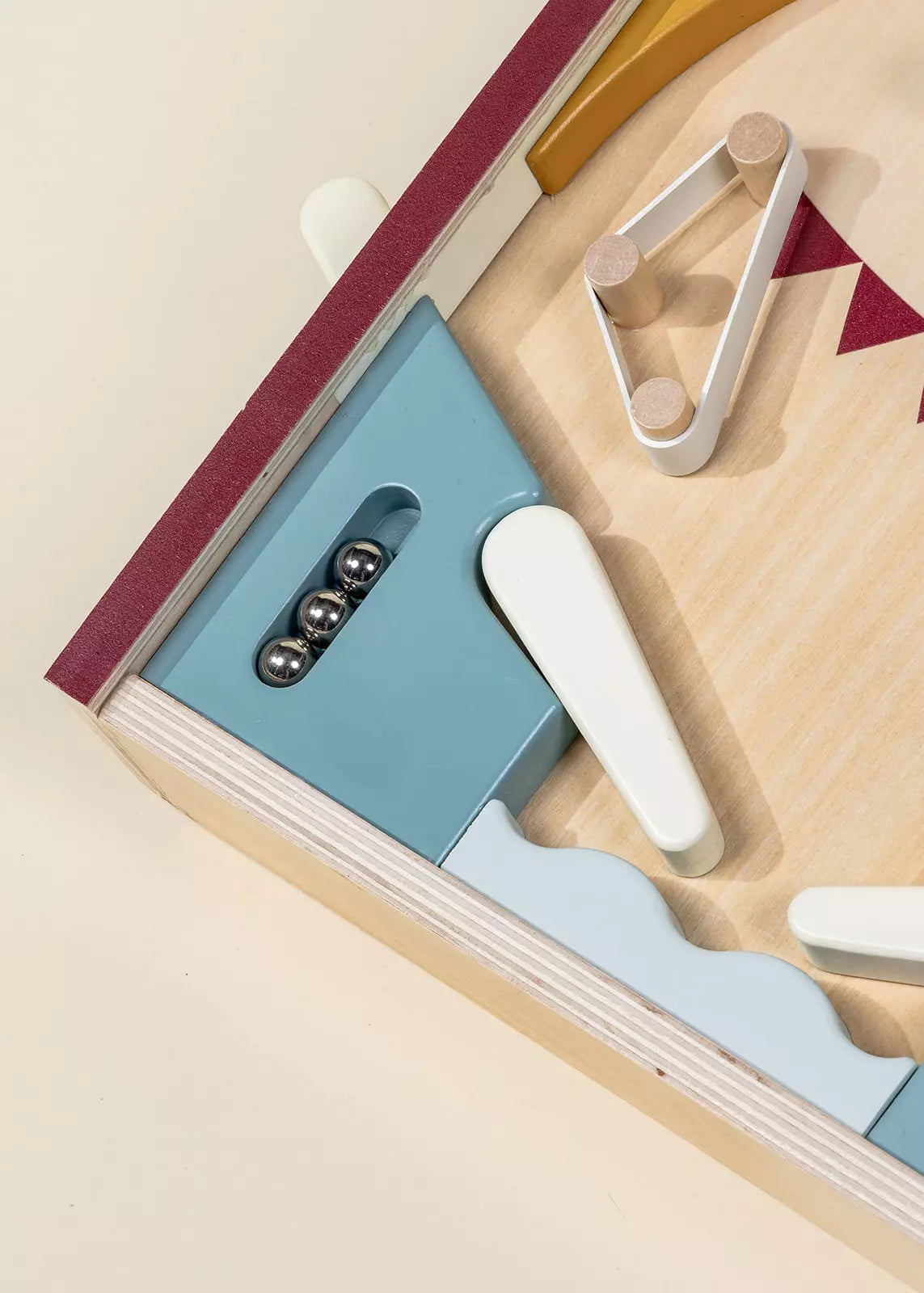 A close-up of the Coco Village Wooden Play Pinball Machine highlights metal balls, white flippers, and geometric bumpers on a light wood surface, showcasing the timeless charm of this screen-free toy.