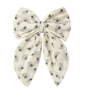 The Rylee & Cru Girls’ Oversized Bow features long tails and a beige background decorated with a delicate pattern of small black and gray flowers. This charming accessory is finished with an alligator clip for secure and easy styling.