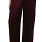 Someone wearing the Simkhai Kyra Wide Leg Pant, featuring a high-waisted fit and tailored waistband, with hands in pockets and open-toe sandals.