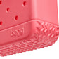 Close-up of the corner of a pink, textured rubber Bitty Bogg® Bag by Bogg Bags, featuring the embossed “bogg” logo and ventilation holes above a treaded bottom—highlighting this stylish, washable compact tote.