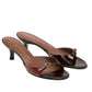The Crackle Shine Kitten Heel by Dorothee Schumacher features brown crinkle patent leather, open toes, signature buckled straps, and branded insoles.