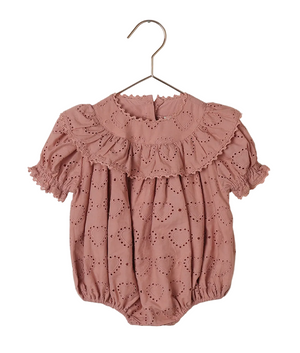 The Noralee Baby Girls' Eva Romper, featuring pink heart eyelet fabric, puff sleeves, a frill collar, lace trim, and elastic leg openings, is displayed on a hanger.