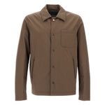The Herno Crinkle Cotton Shirt Jacket is a brown, long-sleeve button-up with a collar, single chest pocket, and two zippered side pockets, featuring a minimalist design and shown on a plain white background.
