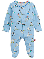 The Magnetic Me Baby Boys’ Ruff Riders Footie is a blue onesie crafted from naturally flame-retardant RightFit fabric, featuring a playful print of dogs wearing hats—some riding skateboards and others standing. It offers a front snap closure and a loose-fitting Footie design for added comfort.