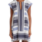 A woman wears the Lemlem Elina Caftan, a hand-woven cotton Ethiopian dress with short sleeves, knee-length cut, blue and white stripes, and a frayed hem.