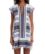 A woman wears the Lemlem Elina Caftan, a hand-woven cotton Ethiopian dress with short sleeves, knee-length cut, blue and white stripes, and a frayed hem.