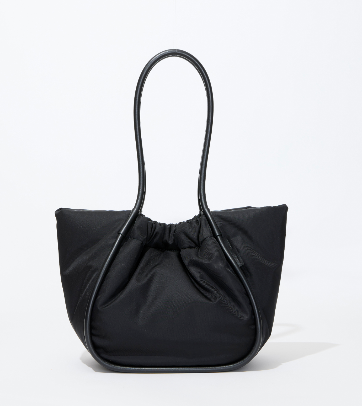 The Proenza Schouler Large Ruched Puffy Nylon Tote in black features a structured curved handle, gathered top, and gold-tone logo stamp, shown against a plain white background.