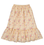 The Girls’ Rachel Skirt by Louis Louise is a light yellow cotton maxi skirt with a floral print in pink and blue, featuring an elastic waistband and a ruffled hem.