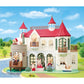 The Calico Critters Red Roof Riverside Manor is a white, castle-style house with red roofs, featuring charming animal figurines posed in the windows, on balconies, and throughout the yard surrounded by greenery and a river beneath a blue sky.