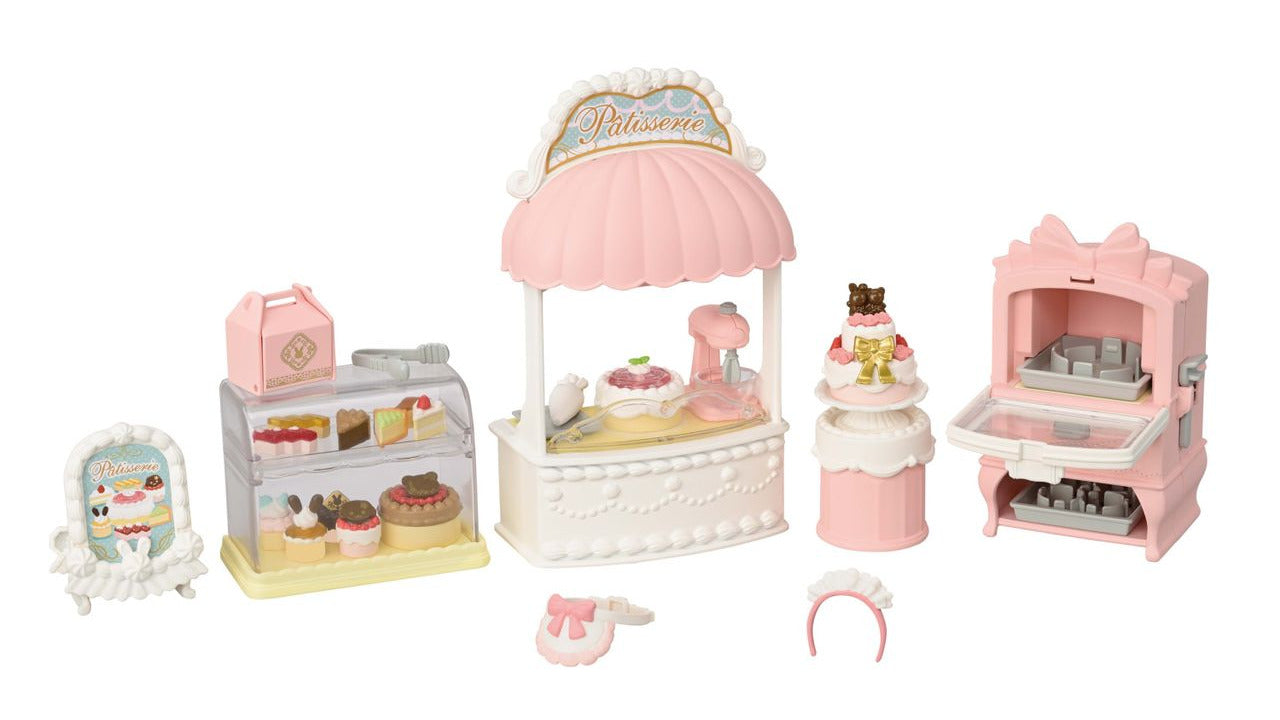 Introducing the Calico Critters Village Cake Shop Starter Set—a delightful miniature pink and white bakery playset featuring a display case, desserts, mixing stand, oven, and adorable baking accessories. Perfect for creating your own sponge cakes and practicing cake decorating skills, just like in a real cake shop!.