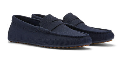 A side view of Peter Millar's Cruise Knit Driver shows timeless navy blue loafers with textured fabric and tan soles.