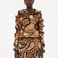 A person stands facing forward in a long-sleeved Ulla Johnson Sunara Pullover and skirt, featuring an orange, black, and beige paisley pattern in Italian cotton, set against a plain white background.