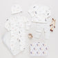 The Nesting Box Baby Take Home Set by Pink Chicken includes animal-print organic pima cotton pajamas, a hat, striped blanket, wooden teether, stuffed toy, and a matching storage bag—all displayed on a white background.