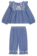 The Louise Misha Baby Girls’ Mikani Set is a charming two-piece toddler outfit, showcasing a cotton Oxford design with a long-sleeve blue top embellished with delicate white floral embroidery, paired beautifully with matching blue pants featuring an elastic waist and embroidered hem details for a coordinated look.