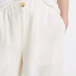 A person wears vince’s Hemp Utility Pant in breathable off-white linen-hemp with a wooden button, hands in pockets, and pairs it with a tucked-in white shirt for a relaxed silhouette.
