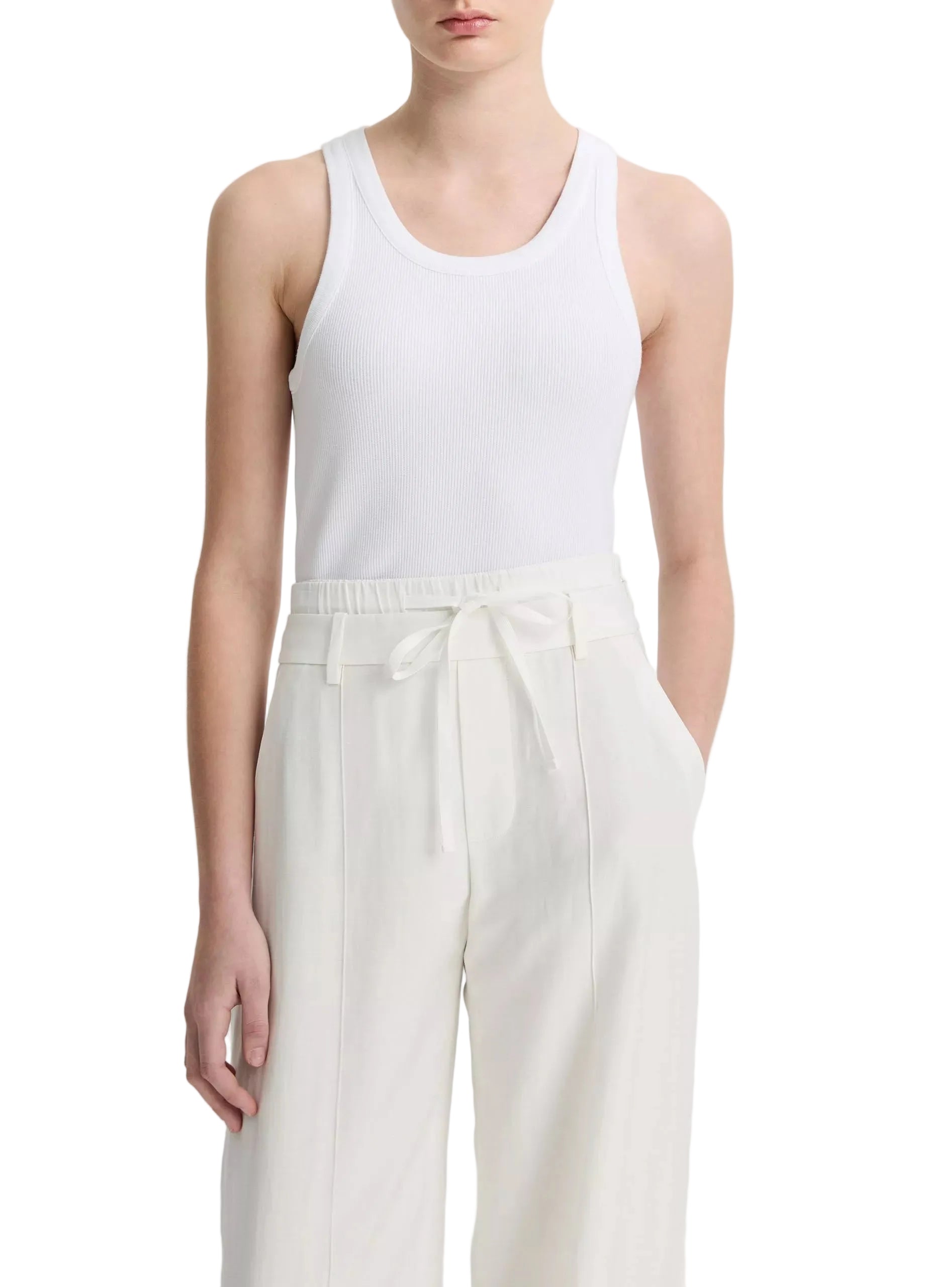 A person wearing the vince Ribbed Scoop Neck Tank in white and high-waisted white pants with a tie belt, standing against a plain background.