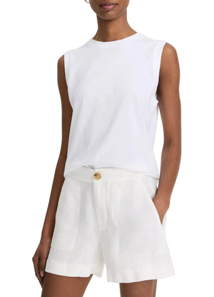 A person wearing a sleeveless white top and vince Mid Rise Hemp Shorts with a button closure stands with one hand in their pocket.