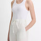 A person is wearing the vince Ribbed Scoop Neck Tank—a white, finely ribbed tank top made from a soft cotton modal blend—paired with high-waisted white drawstring pants, standing against a plain background.