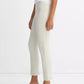 A person wearing vince’s Bobbi Mid Rise Pant in off-white, crafted from Italian cotton-blend ponte, styled with a sleeveless white top and beige heeled sandals, stands against a plain white background.