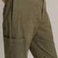 Close-up of a person wearing the vince Owen Side Pocket Trouser in olive green, featuring a visible side pocket, paired with a tucked-in, vertically striped shirt.