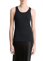 A person wearing the vince Ribbed Scoop Neck Tank—a finely ribbed, black sleeveless top made from a soft cotton modal blend—paired with a black skirt and standing against a plain white background.