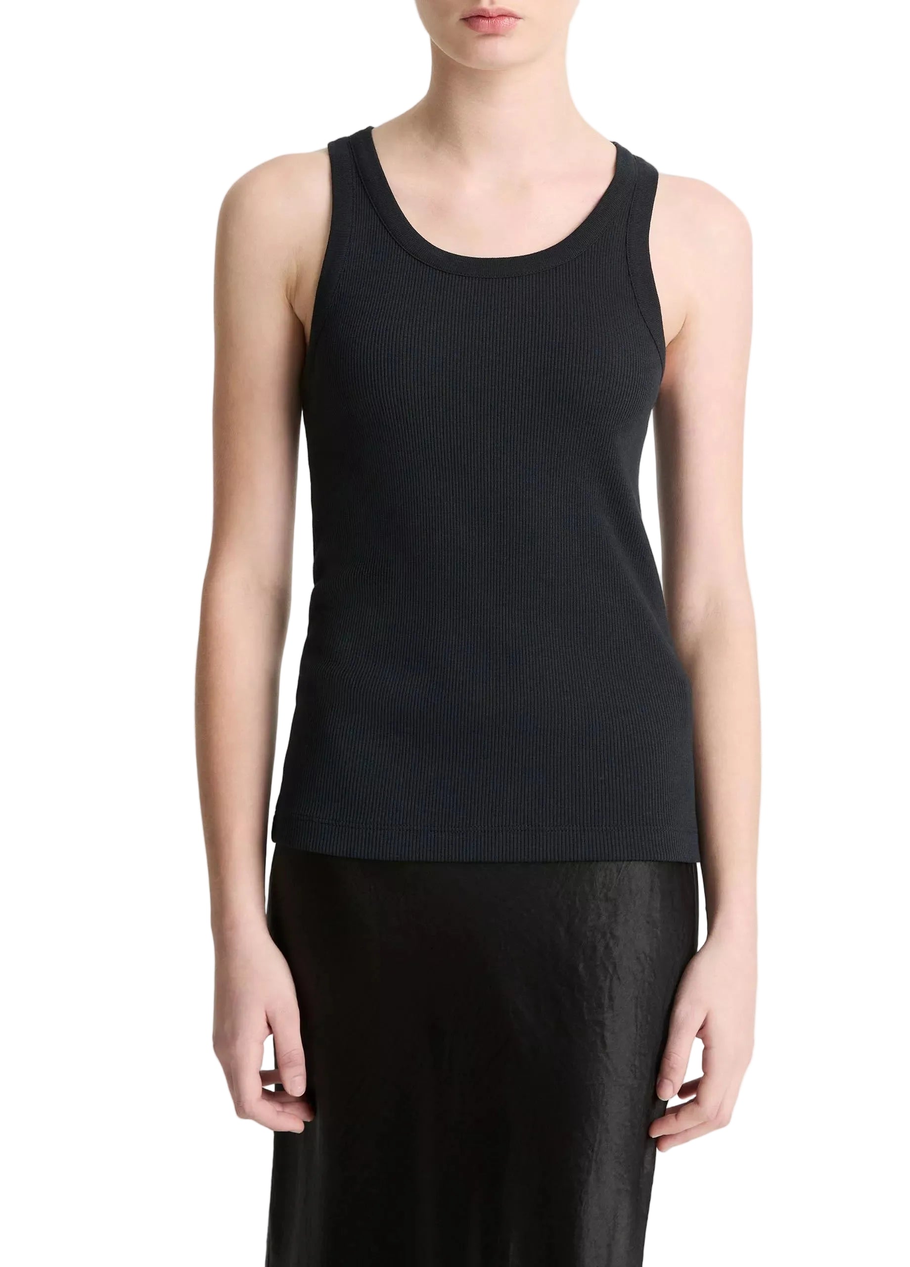 A person wearing the vince Ribbed Scoop Neck Tank—a finely ribbed, black sleeveless top made from a soft cotton modal blend—paired with a black skirt and standing against a plain white background.