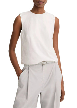 A person wears the Vince Linen Crew Neck Shell Tank and high-waisted light gray linen-blend trousers with a belt, standing with one hand in a pocket.