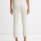 A person wearing light-colored, fitted Bobbi Mid Rise Pants by vince, crafted from an Italian cotton-blend ponte with back slits, paired with beige heeled sandals and a white sleeveless top, is shown from the back against a plain background.