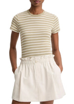 A person wears the vince Stripe Shrunken 90s Tee—a short-sleeve, tan and white striped top in a shrunken fit—paired with a high-waisted, cream-colored skirt, hands in pockets.