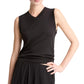 Wearing the Vince High V-Neck Shell Tank in black and a pleated black skirt, a person poses with one hand on their hip against a white background.