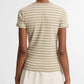 A person stands facing away, wearing the Vince Stripe Shrunken 90s Tee in beige and white stripes paired with a light-colored skirt, set against a plain background.