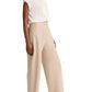 A person wears a short-sleeve white blouse tucked into the vince Colette Linen Bias Pant—high-waisted, wide-leg beige pants crafted from Italian linen and featuring a hidden elastic waistband—paired with beige heeled sandals, standing against a plain white background.