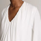A model is shown from the shoulders to the chest against a neutral background, wearing the Vince Matte Jersey V-Neck Bubble Top in white, offering a minimal interpretation of classic style.