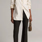 Model wearing a light-colored pinstripe button-down shirt, black Vince Niki Mid Rise Crop Flare Pant, cream-colored slingback heels, and a small handbag.
