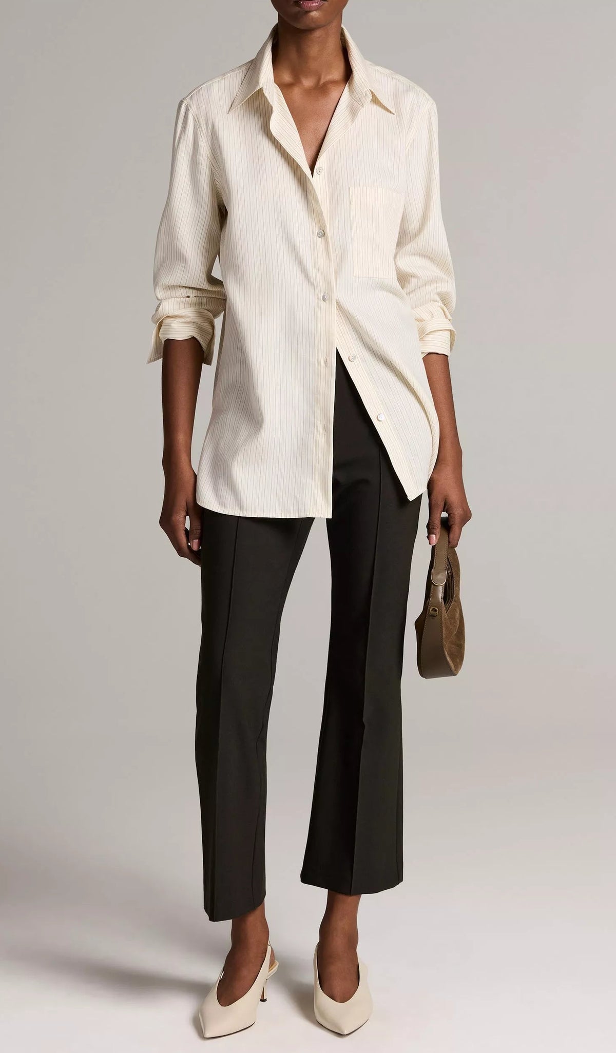 Model wearing a light-colored pinstripe button-down shirt, black Vince Niki Mid Rise Crop Flare Pant, cream-colored slingback heels, and a small handbag.