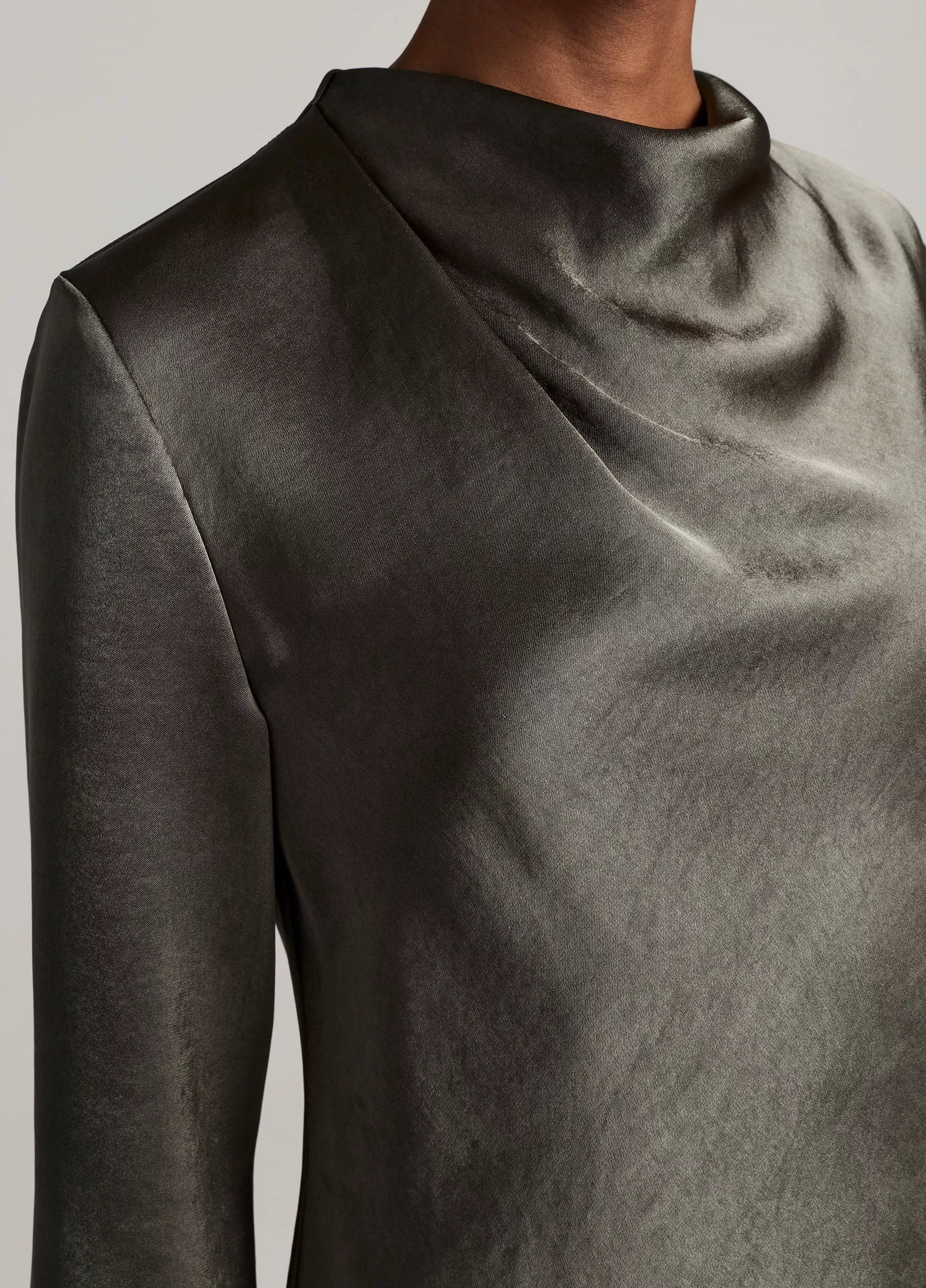 Close-up of a person wearing the Vince Long Sleeve Draped Cowl Blouse in dark gray, featuring a softly draped and pleated neckline.