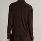A person is seen from the back wearing the vince Long Sleeve Draped Cowl Blouse in dark brown matte jersey, featuring a center back seam and a high neckline.