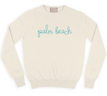 The Lingua Franca Palm Beach Classic Longsleeve Crewneck is a cream cashmere sweater with "palm beach" in light blue cursive on the front, ethically crafted for conscious fashion enthusiasts.