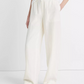 Person wearing Vince Hemp Utility Pant in white with a relaxed fit, styled with a white top and black sandals, standing against a plain light background.