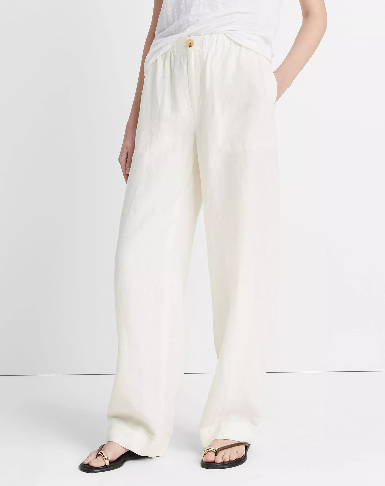 Person wearing Vince Hemp Utility Pant in white with a relaxed fit, styled with a white top and black sandals, standing against a plain light background.