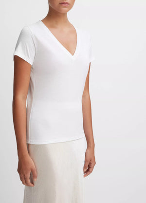 A person wearing the vince Essential V-Neck—a short-sleeved white T-shirt made from luxurious Peruvian Pima cotton—and a white skirt stands against a plain white background.