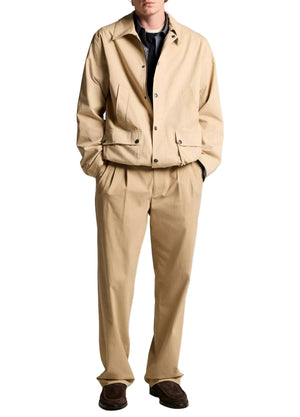 A person wearing the vince Lightweight Barn Jacket in tan with matching tan trousers, hands in pockets, dark shoes, and a partially visible dark shirt and tie, stands against a white background.