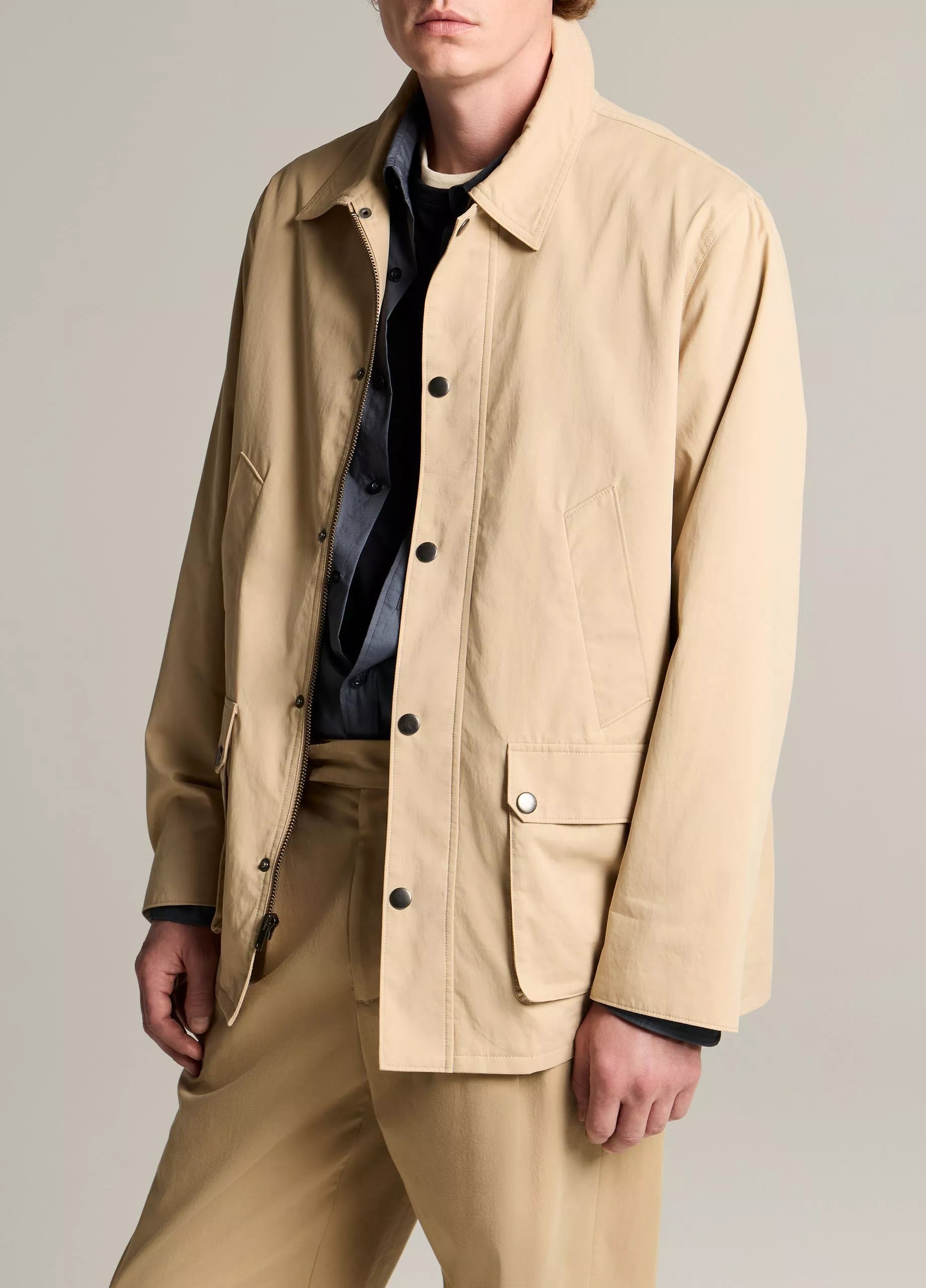 A person wearing the Vince Lightweight Barn Jacket in beige peached cotton with matching trousers over a dark shirt, standing against a neutral background.