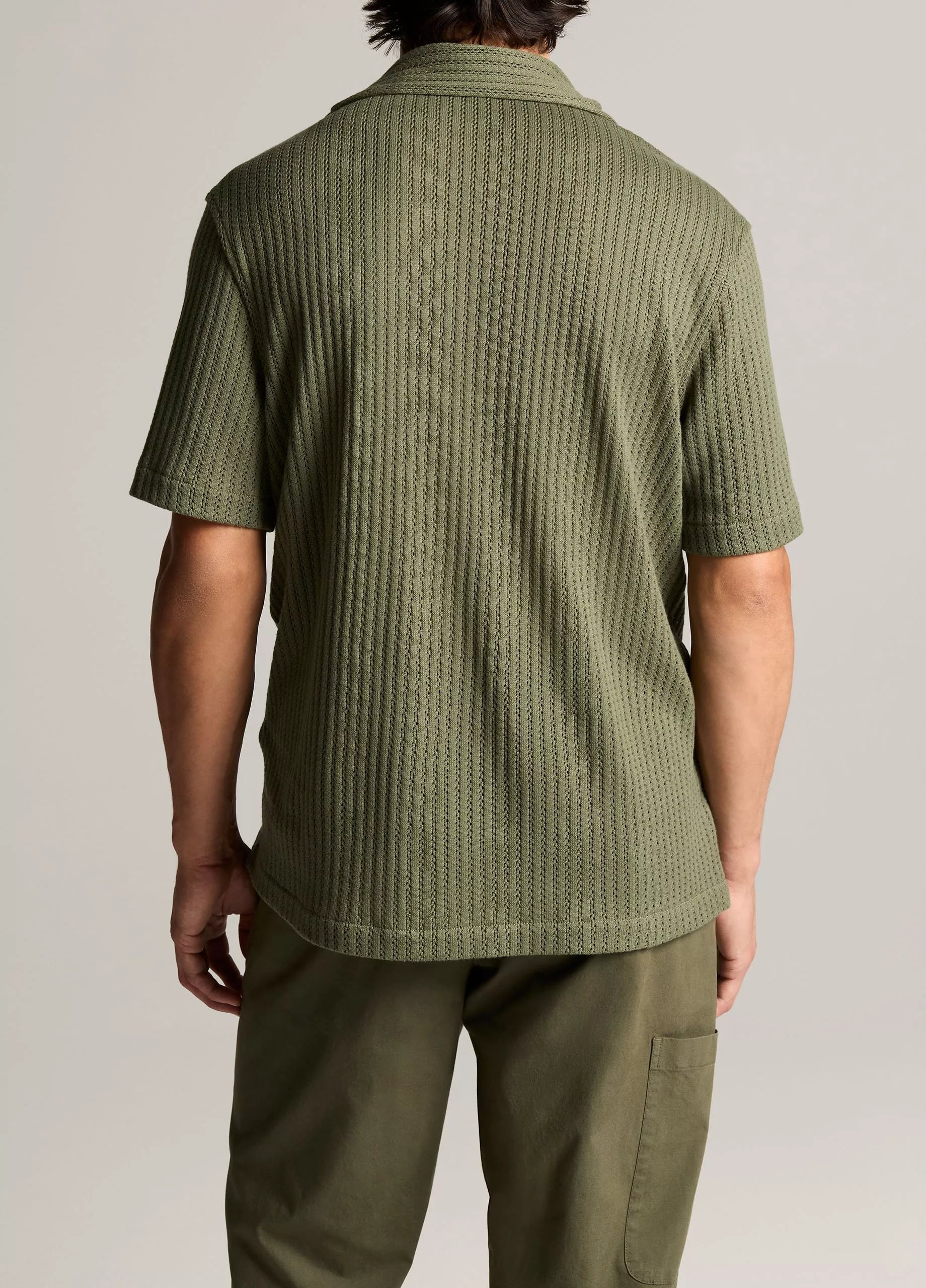 A person is shown from behind wearing the vince Pointelle Short Sleeve Button Down in olive green, paired with matching pants against a plain background.