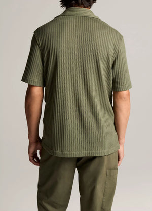 A person is shown from behind wearing the vince Pointelle Short Sleeve Button Down in olive green, paired with matching pants against a plain background.